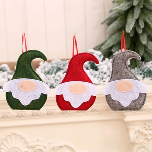 Trois ornements gnomes de Noël nordiques en feutrine rouge, vert et gris sur la cheminée
