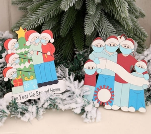 Detail of wooden Christmas ornament featuring masked family and The Year We Stayed Home text