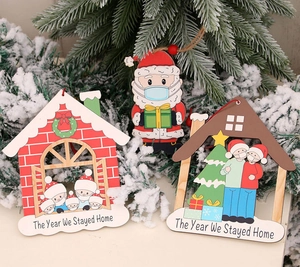 Dettaglio di decorazioni natalizie in legno appese a un albero innevato con design di maschere