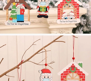 Dettaglio addobbo natalizio in legno con testo The Year We Stayed Home e casa dipinta