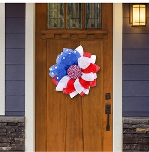 Patriotic July 4th wreath with red white and blue mesh petals hanging on a dark door