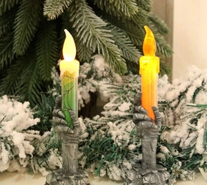 Detail of LED Halloween candles with skull hand bases and flickering flame lighting
