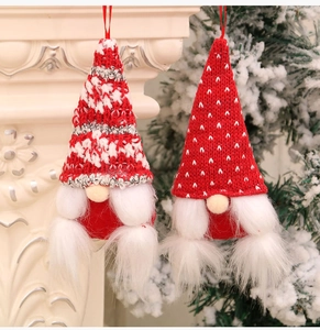 Detail of two knitted Christmas gnomes with long beards hanging on a white fireplace