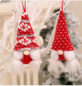 Detail of plush Christmas gnome ornaments with knit hats and faux fur beards on a branch