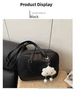 Detail shot of a black leather Boston bag with a white fluffy cloud pendant