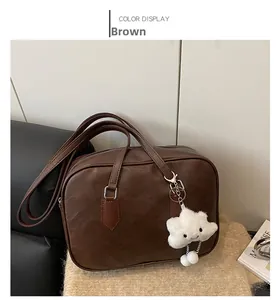 Close-up of a brown Boston bag with double handles and a cute white cloud charm