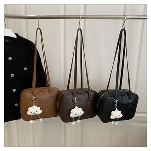 Close-up of leather shoulder bags in brown and black with cloud plush charms