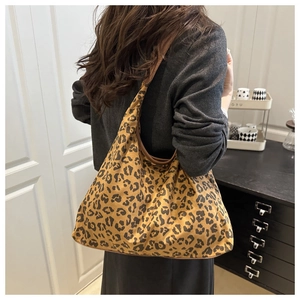 Detail of leopard print tote bag with brown leather straps worn on a grey sweater