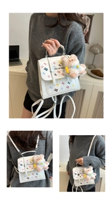 Close-up of white mini backpack with colorful prints and pink teddy bear charm