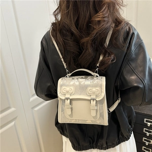 Mini sac à dos chic crème et argent avec nœuds 3D porté par un mannequin en intérieur