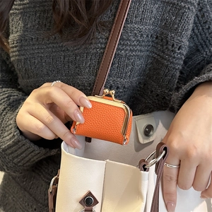 Mini orange pebble leather coin purse with gold metal clasp shown for size comparison