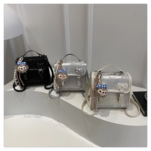Detailed view of mini glitter backpacks in black, silver, and cream with bow accents