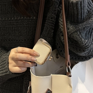 Mini beige pebble leather coin purse with vintage gold clasp tucked into a matching shoulder bag