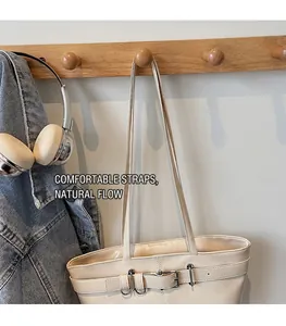 Détail du sac bandoulière en cuir crème avec boucle métallique dans un cadre de style de vie