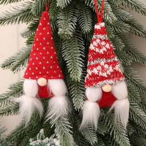 Christmas gnome hanging decorations with red knit hats and white faux fur on a pine tree