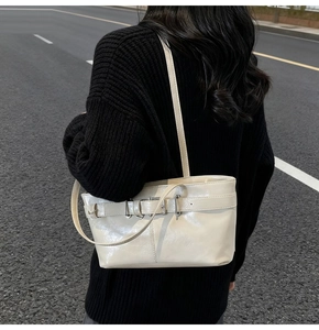 Photo de rue d'un sac cabas en cuir verni crème avec une boucle argentée à l'épaule
