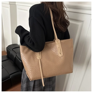 Close-up of light brown tote bag with textured snake-pattern and dual shoulder straps