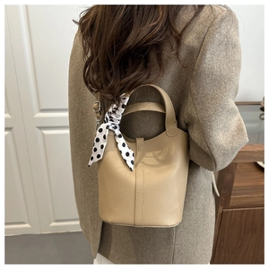 Detail of lychee pattern leather bucket bag with polka dot scarf on a model