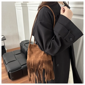 Détail du sac bandoulière en daim marron avec franges longues et bandoulière fine