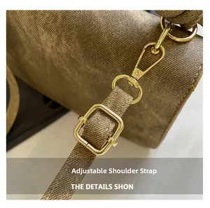 Macro detail of brown textured crossbody bag with adjustable strap and gold metal hardware
