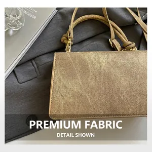 Detail of metallic gold textured fabric handbag with woven strap and golden metal buckle