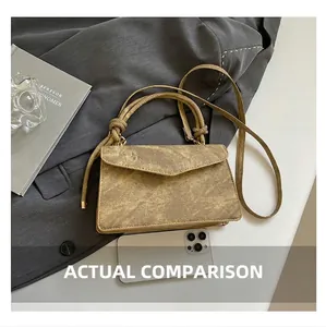 Detail view of vintage metallic envelope bag with knot handle and size reference phone