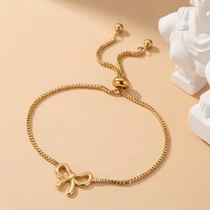Detailed shot of golden bow charm bracelet with adjustable box chain and slider clasp
