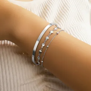 Three-piece stainless steel heart bracelet and open cuff set worn on model's wrist