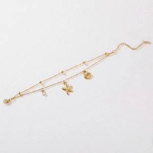 Detail of gold double-layer bracelet with starfish, seashell charms and zircon stones