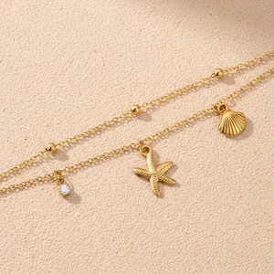 Gold double-layered starfish and shell pendant bracelet with zircon on beach sand