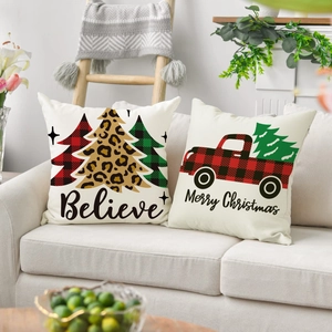 Detail of Christmas pillowcases with festive truck and tree prints on a linen sofa