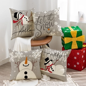 Juego de 4 fundas de cojín navideñas de lino con muñecos de nieve sobre un sillón de cuero