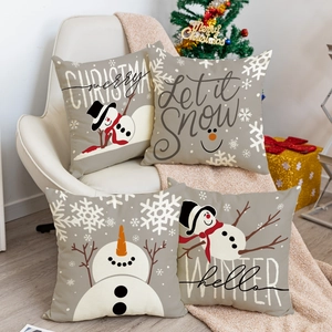 Juego de 4 fundas de cojín navideñas con muñecos de nieve sobre un sofá blanco
