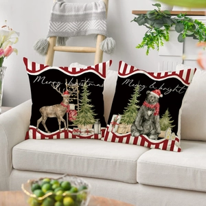 Set of two black Christmas throw pillows with reindeer and bear on a cozy sofa