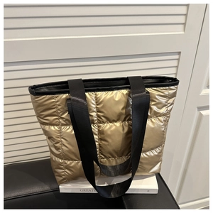 Detail of golden quilted puffer tote bag featuring durable black fabric straps and finish