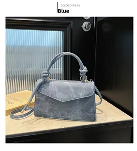 Detail of blue denim textured handbag with knotted handle and golden metal buckles