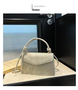 Detailed view of light green trapezoid handbag with knotted handle and gold metal hardware