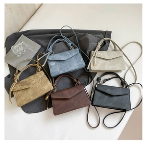 Flat lay of small leather crossbody bags in five Morandi colors on a grey blazer