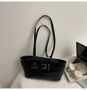 Gros plan du sac porté épaule en cuir noir avec boucle argentée à côté d'un ordinateur