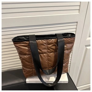 Close-up of brown quilted tote bag showing shiny waterproof fabric and canvas handles