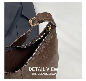 Detail of brown lychee leather shoulder bag showing gold metal buckle and smooth zipper