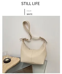 Close-up of white half-moon shoulder bag with lychee texture and gold buckle detail
