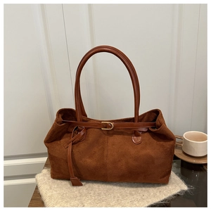 Detail of brown suede tote bag featuring smooth leather straps and gold buckle accents