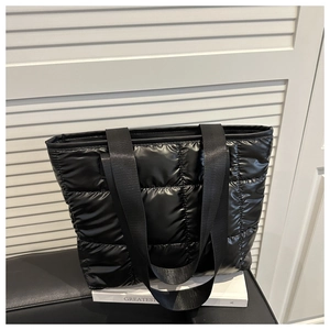 Detailed view of the black quilted puffer tote bag with glossy finish and matching straps
