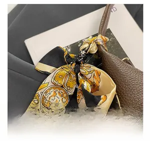 Detail of silk scarf tied on brown pebble leather handbag with citrus fruit pattern