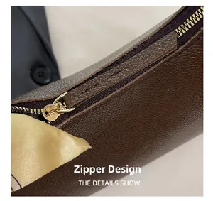 Close-up of golden metal zipper design and silk ribbon accessory on dark brown leather bag