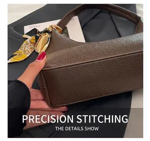 Detail showing precise stitching on brown lychee grain leather bag with decorative scarf