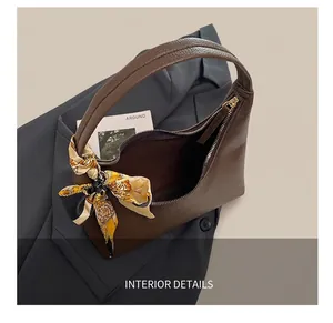 Detail view of large brown leather shoulder bag with decorative silk scarf and gold zipper