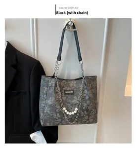 Detail of grey floral tote bag with silver chain and pearls on a white wall hook