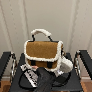 Brown suede saddle bag with white shearling trim and round coin purse on a chair